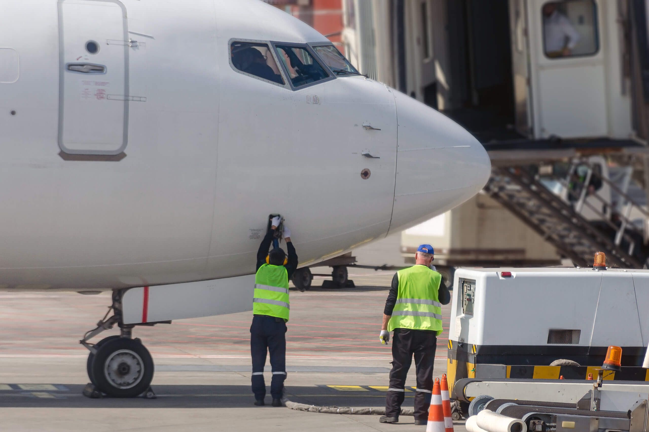 Federal Aviation Administration Drug & Alcohol Testing 2 men in yellow vests hooking a cable to the nose of an airplane