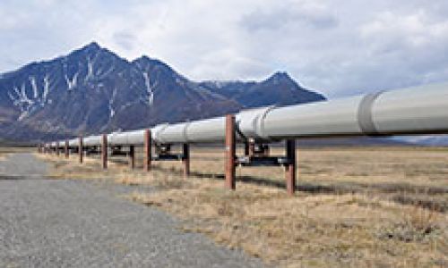 A pipeline going through the desert surrounded by mountains