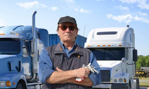 Truck driver standing in front of 2 semi truck