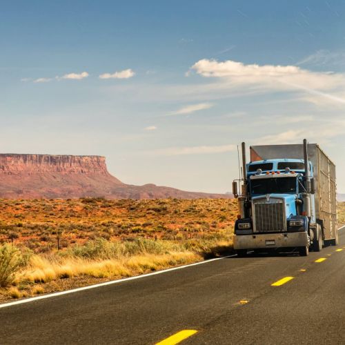 Semi truck driving through the desert in Arizona with red rocks in the background