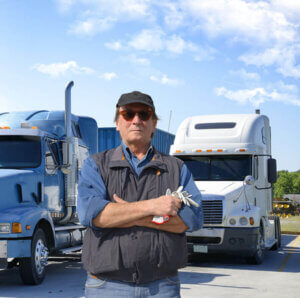 Truck driver standing in front of 2 semi truck