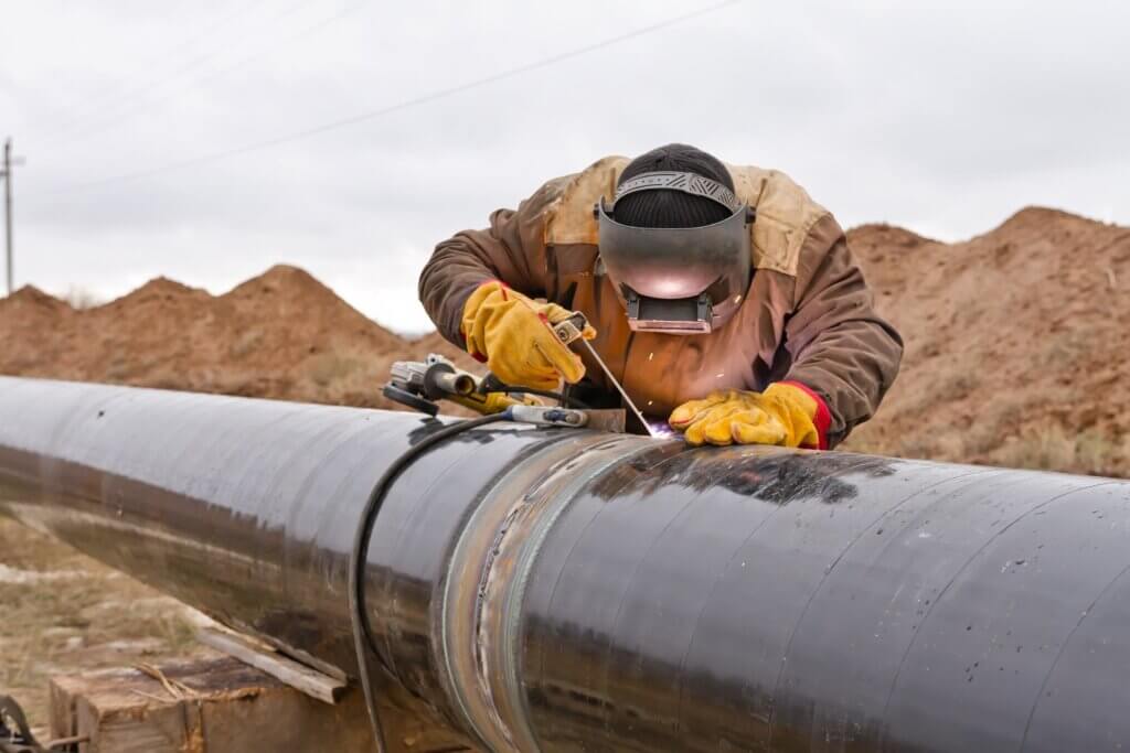 Welder working on an outdoor pipeline