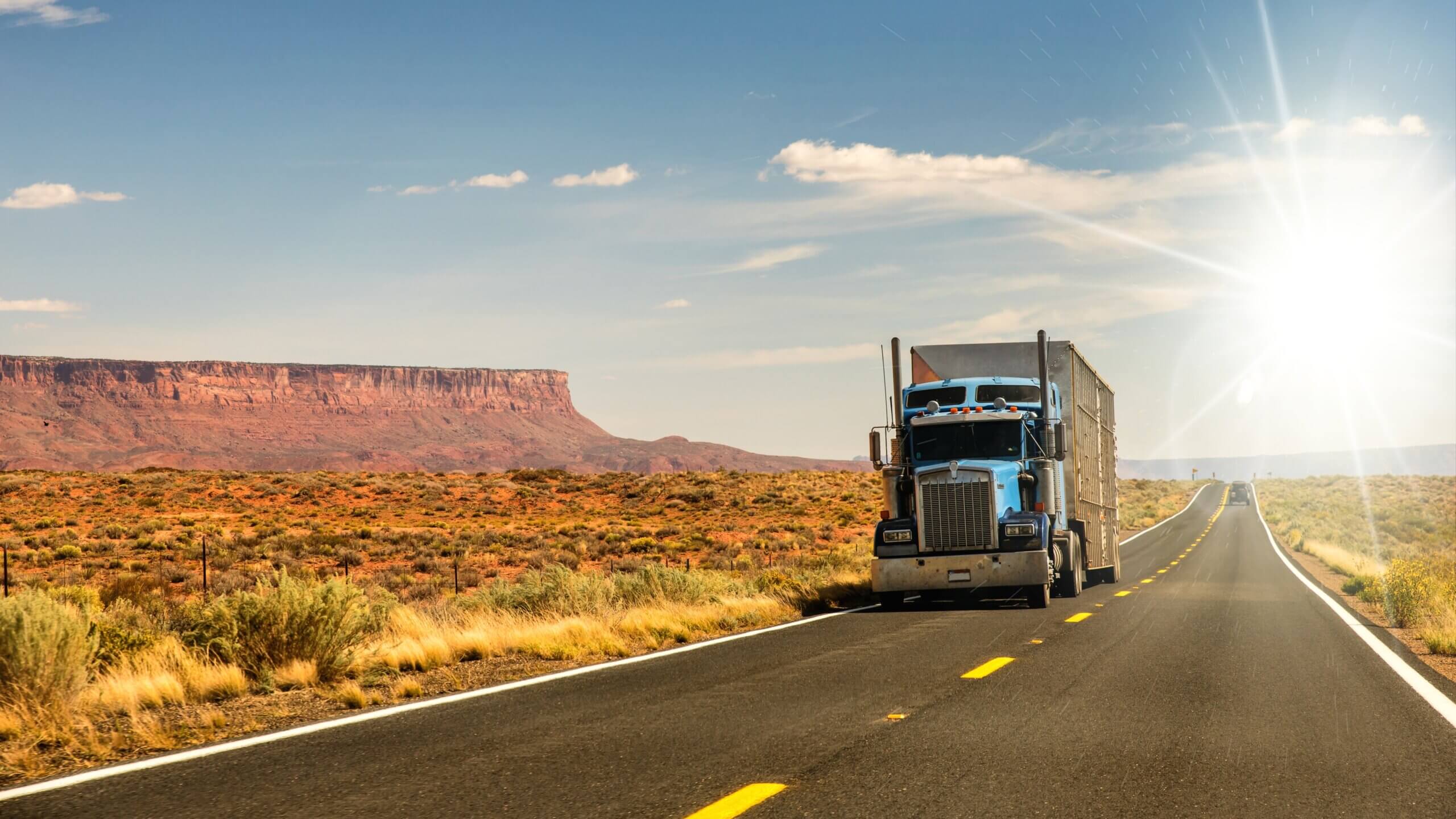 Semi truck driving through the desert in Arizona with red rocks in the background