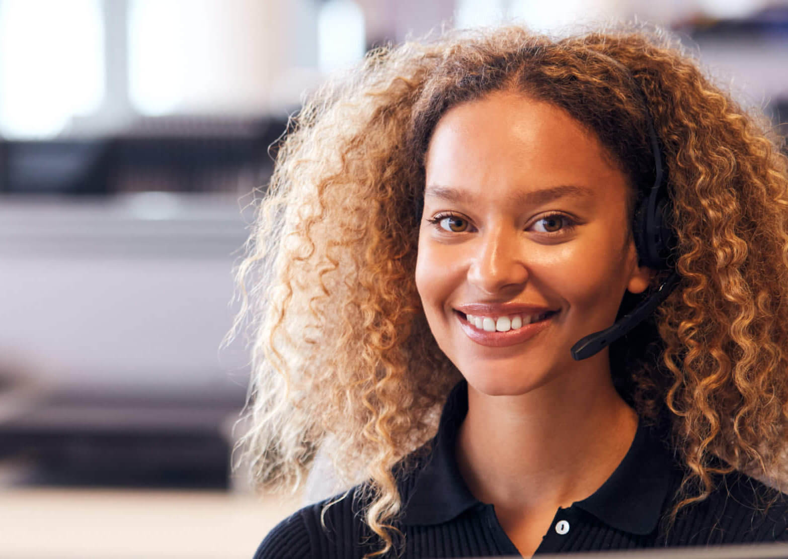 Female customer service worker smiling and wearing a headset