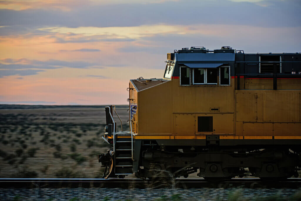 Cargo train crossing an open field at sunset