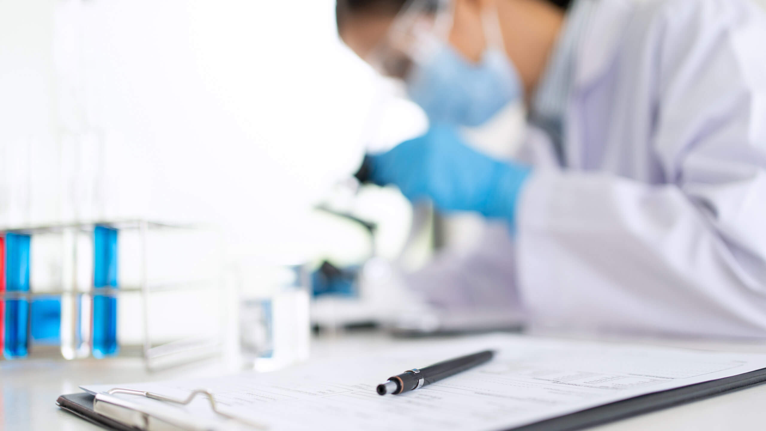 A lab technician viewing a sample under a microscope