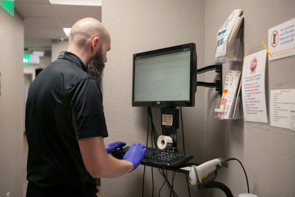 A male medical professional inputting patient results into a computer