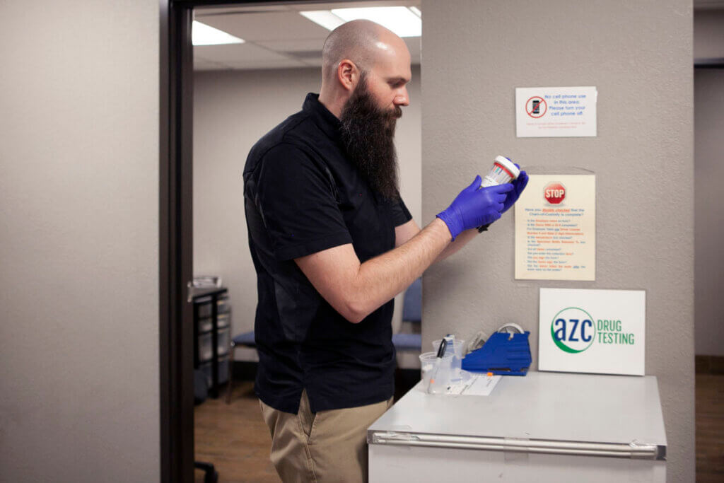 Male medical professional preparing a patients collection cup for drug testing