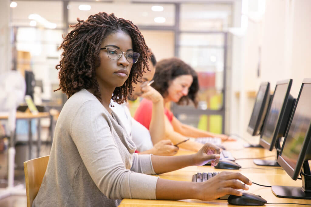 3 young people sitting in a computer lab working together