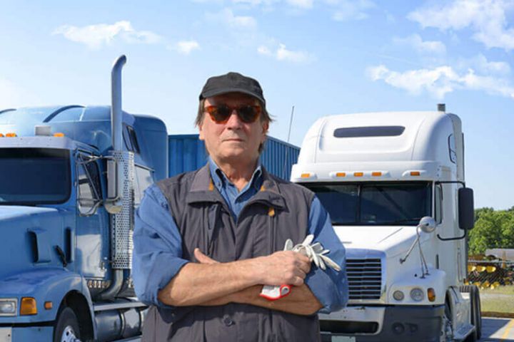 Truck driver standing in front of 2 semi truck