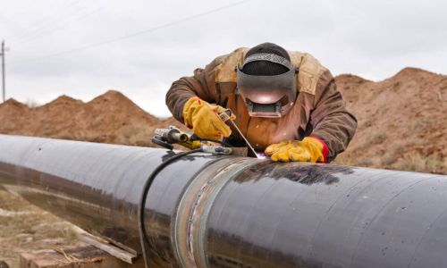 Welder working on an outdoor pipeline