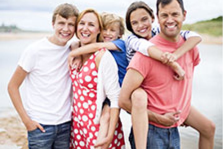 Happy parents with 3 smiling children by the beach