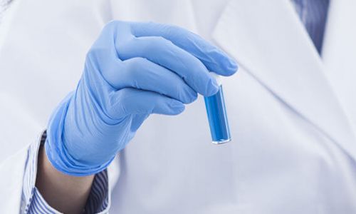 Lab technician holding a test tube with blue liquid