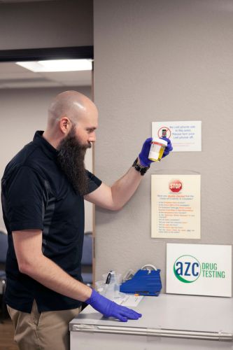 Male medical professional preparing a patients collection cup for drug testing