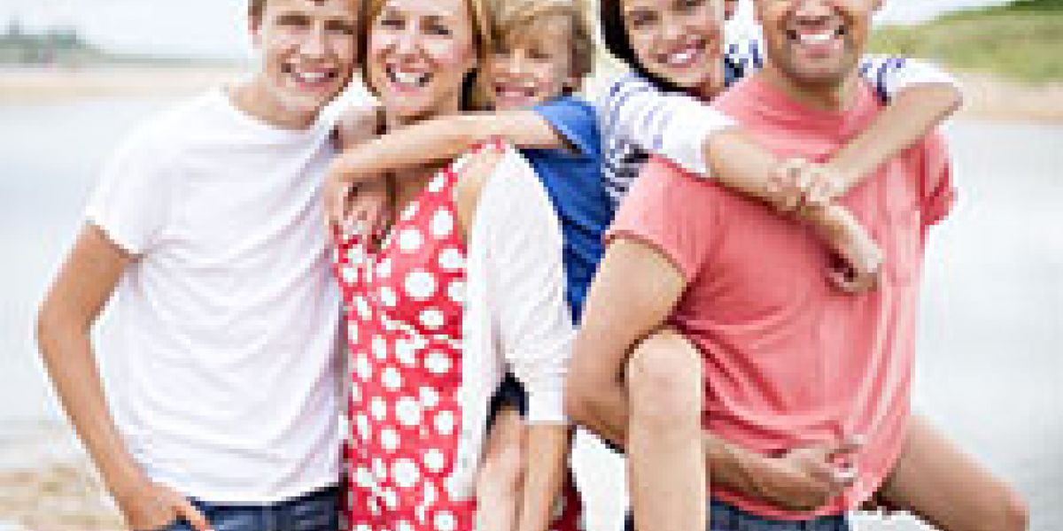 Happy parents with 3 smiling children by the beach