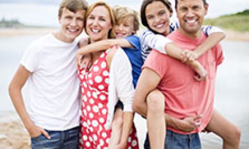 Happy parents with 3 smiling children by the beach