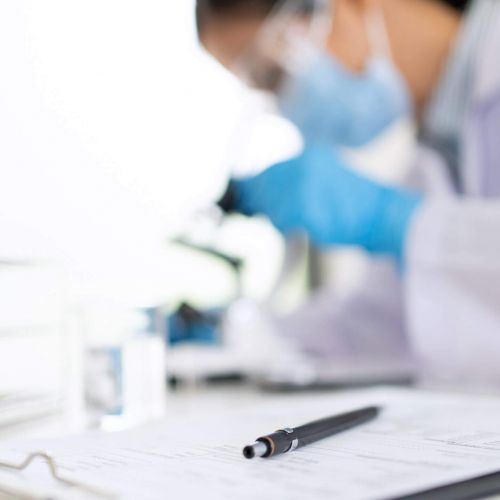 A lab technician viewing a sample under a microscope