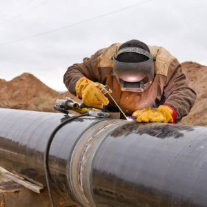 Welder working on an outdoor pipeline