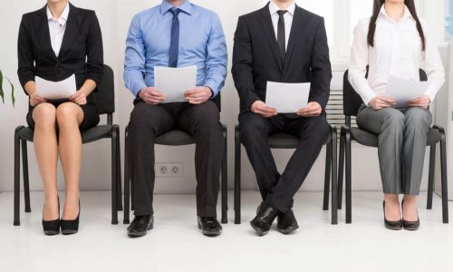 4 people sitting in a lobby holding papers waiting for interviews