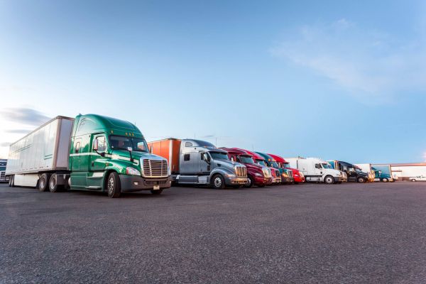 A row of different colored semi-trucks parked at a truck stop