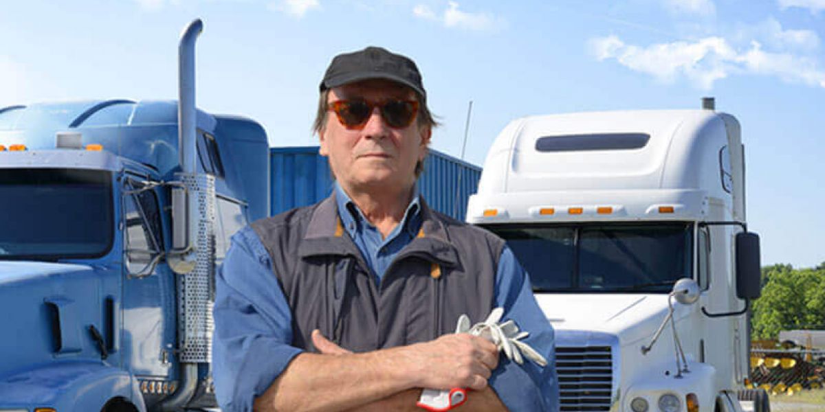 Truck driver standing in front of 2 semi truck