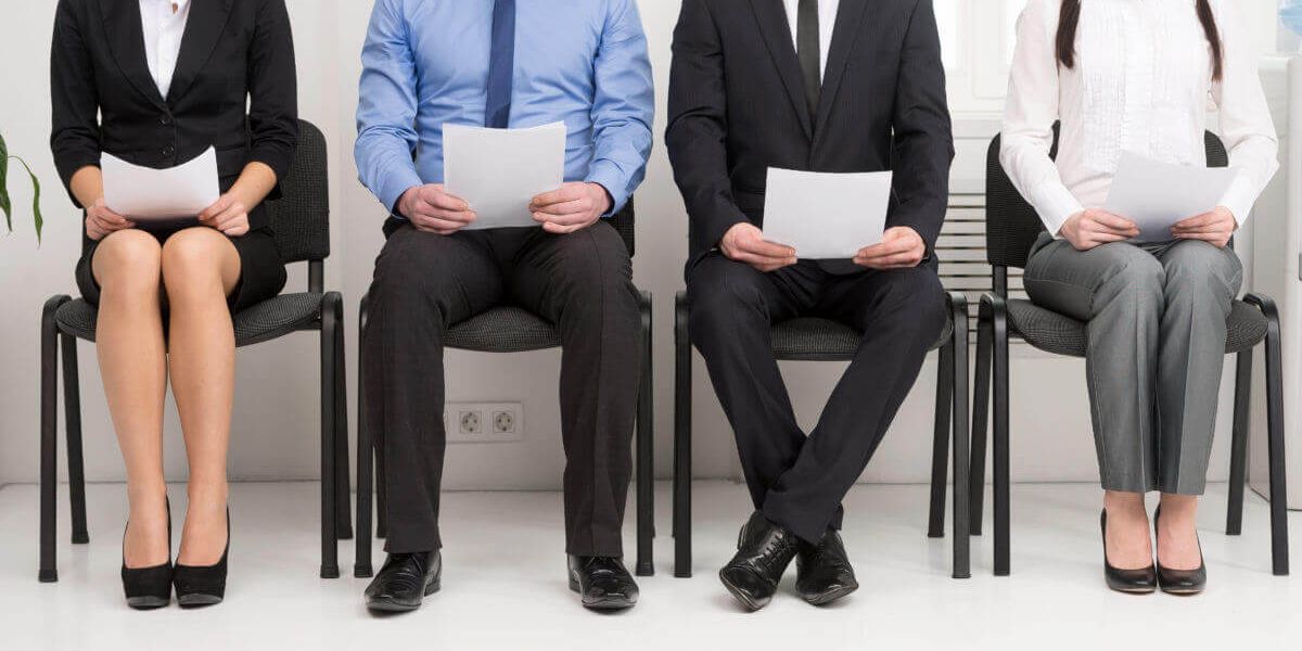 4 people sitting in a lobby holding papers waiting for interviews