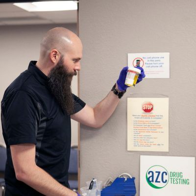 Male medical professional preparing a patients collection cup for drug testing