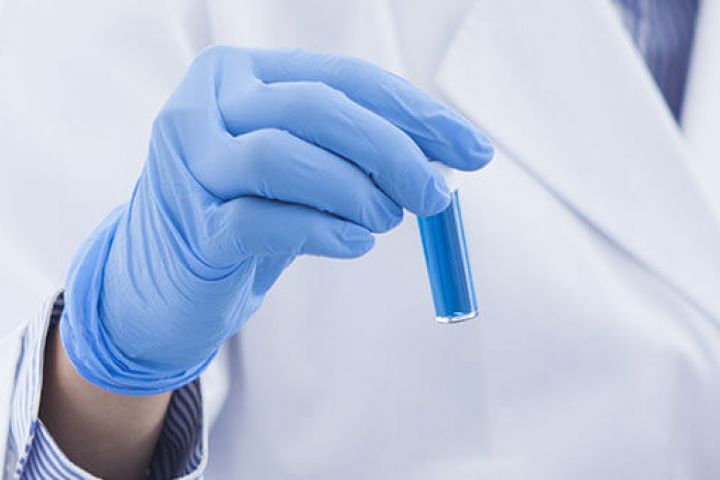Lab technician holding a test tube with blue liquid
